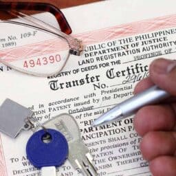 Transfer certificate with a man's hand holding a pen, keys and glasses on top